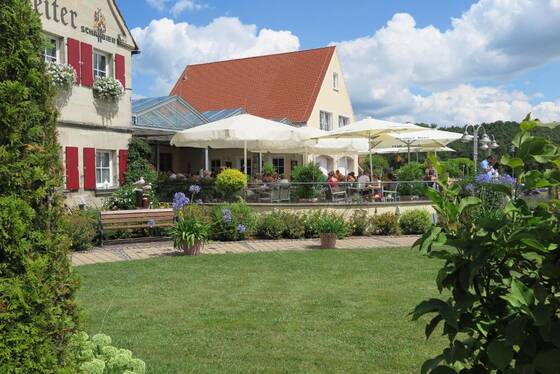 Terrasse des Restaurants Zum Hochreiter mit Sonnenschirmen und G&auml;sten